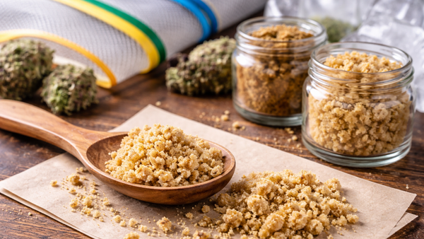 Bubble hash concentrate with cannabis buds and filtration bags on a wooden table.