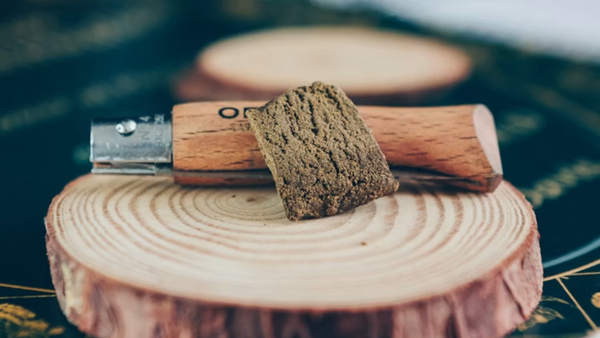 Close up of a pressed hash block resting on a wooden surface.