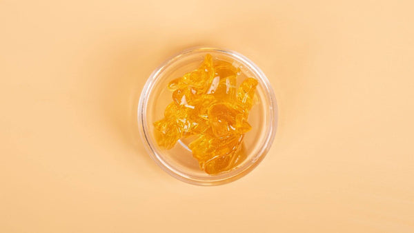 Close-up of premium THCA hash rosin concentrate in a glass container.